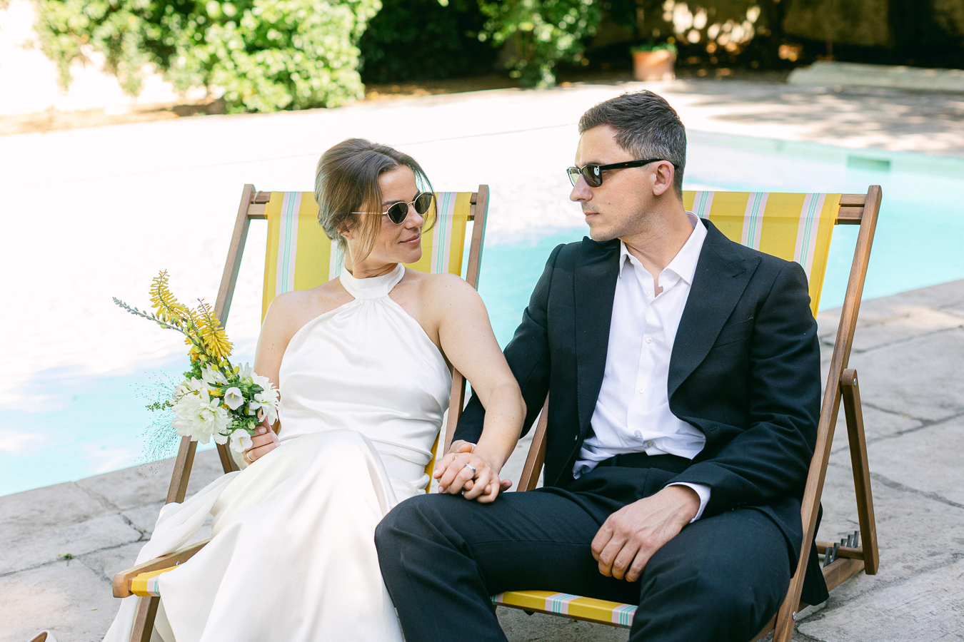 Couple en tenue de mariage assis sur des transats, ambiance élégante et décontractée
