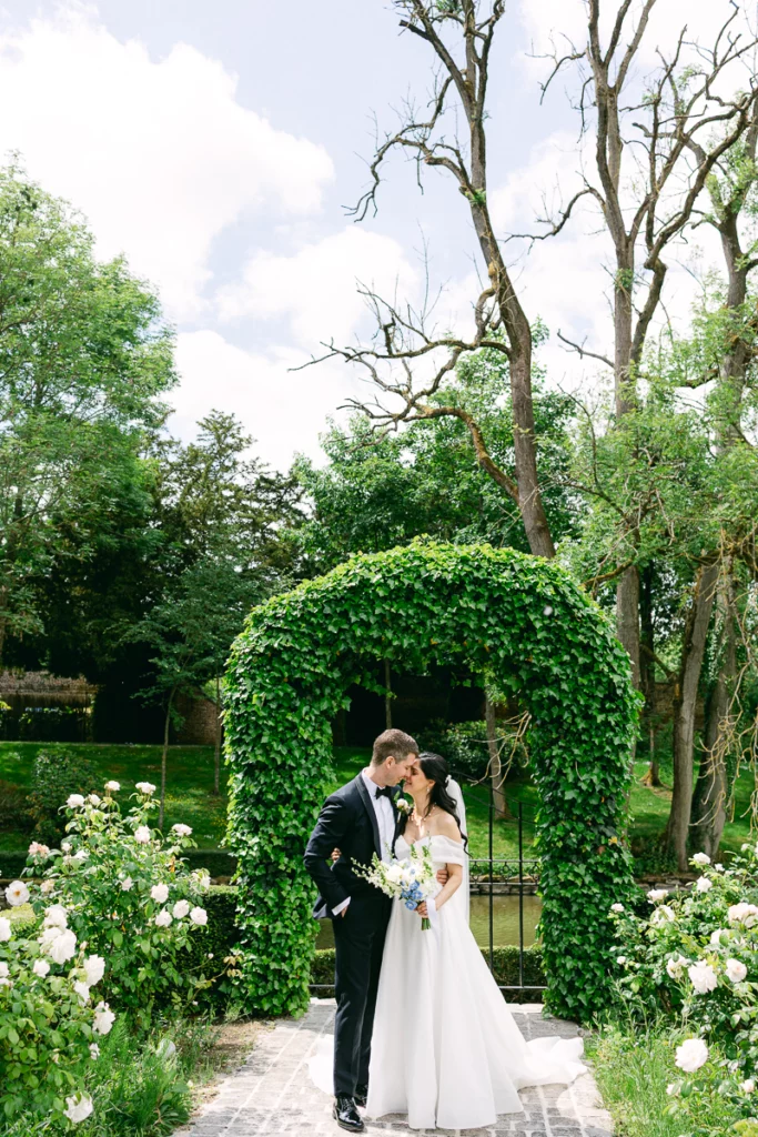 Couple de mariés sous une arche végétale, photo de mariage en Belgique
