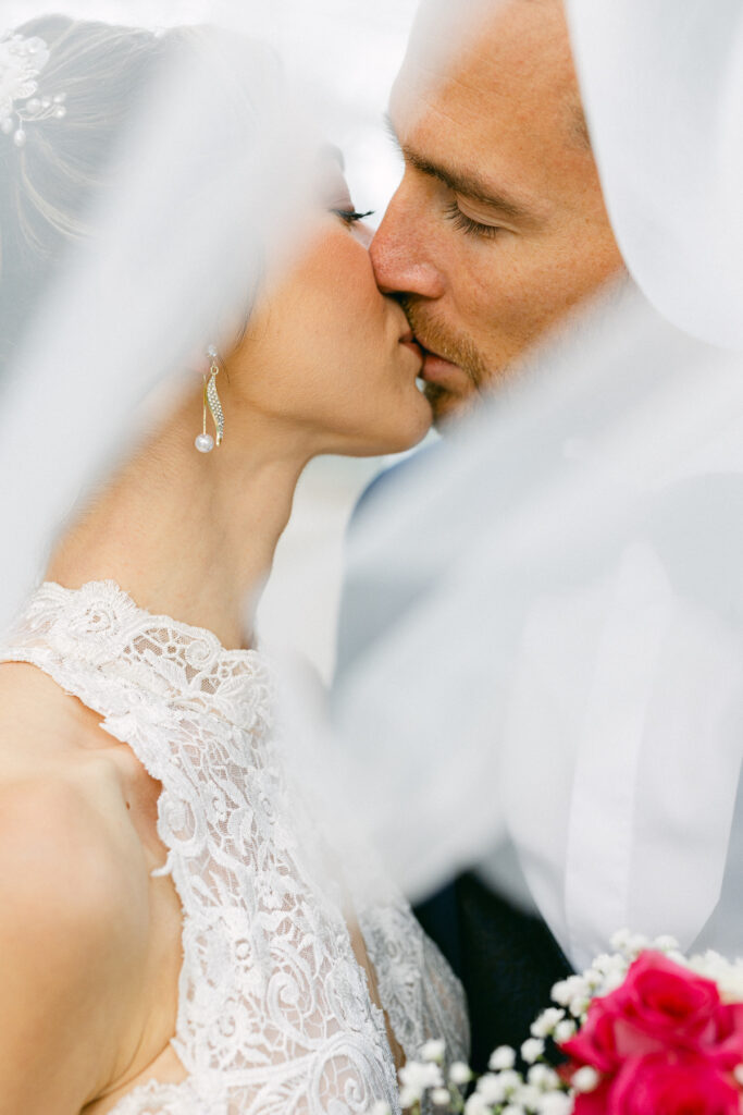 Gros plan des mariés qui s’embrassent sous le voile, style fine art